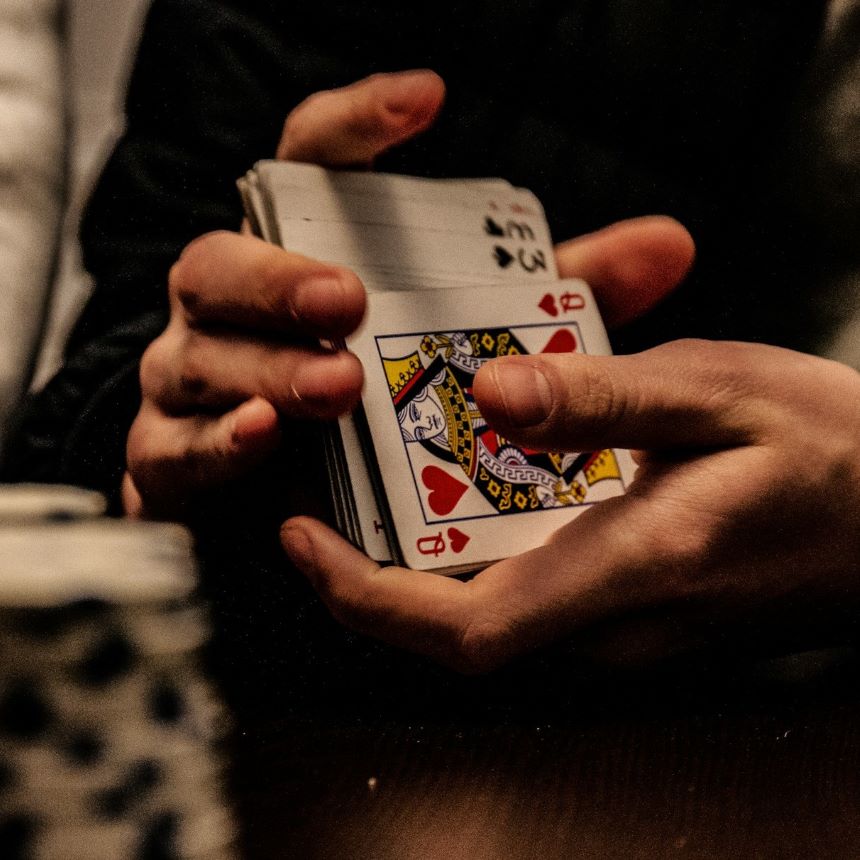 A person shuffles a deck of cards in front of poker chips.