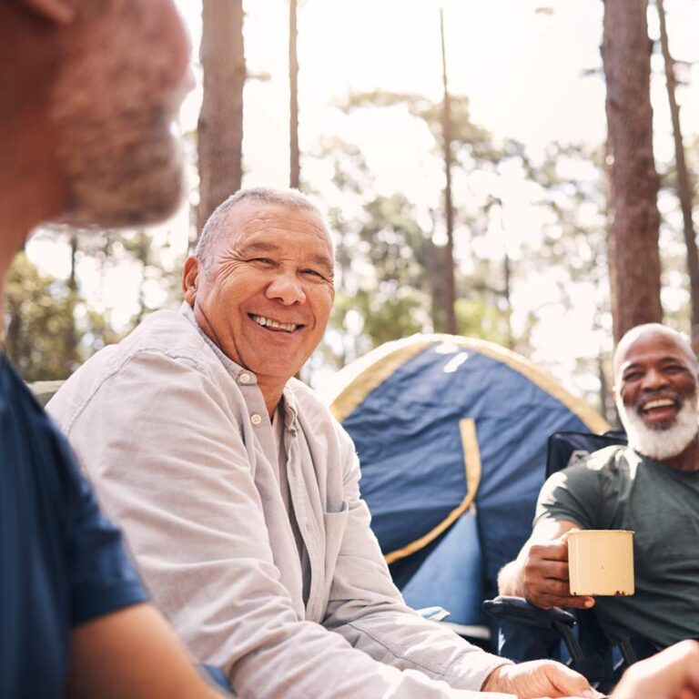 A group of people sit around a campground with warm coffee and smiles